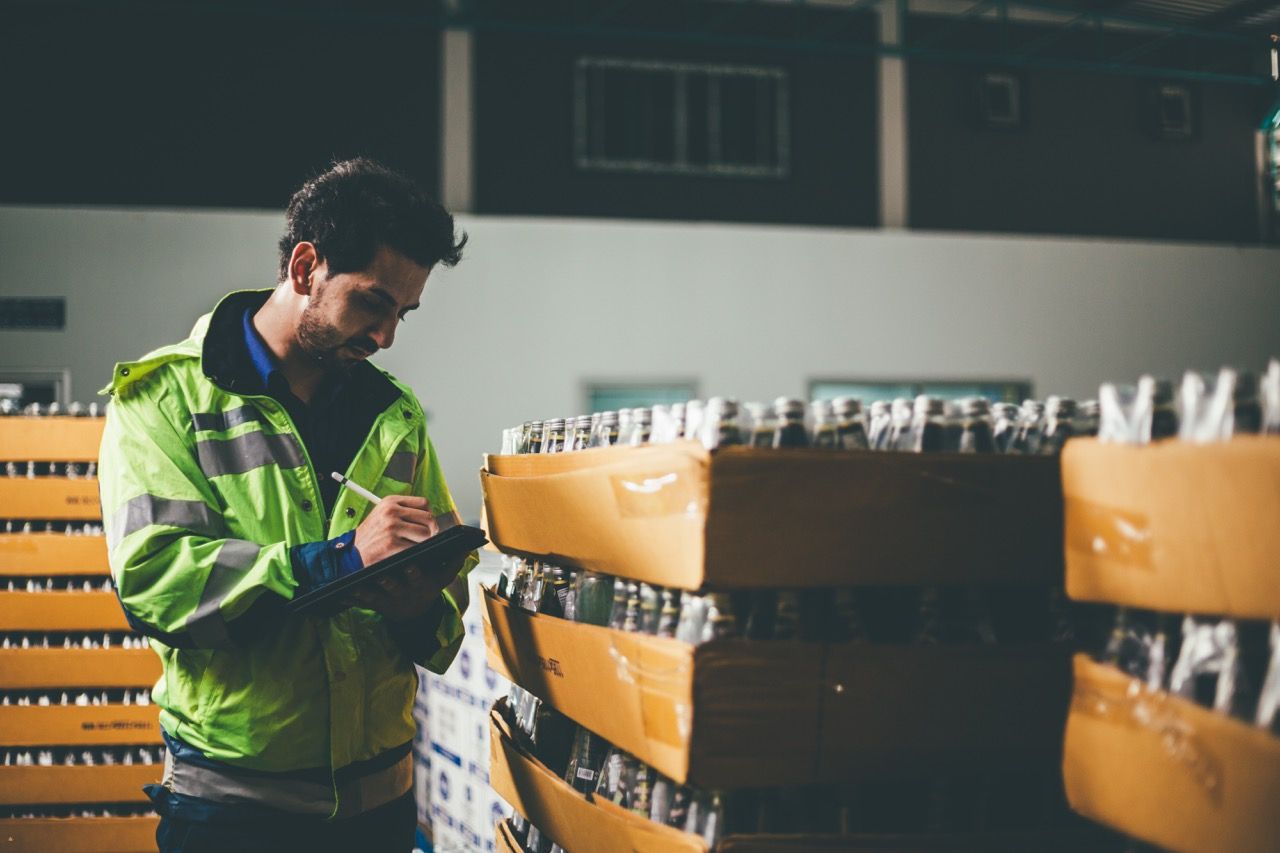 Male supervisor checking quality control of drinking bottle Avada Caterer Mobile App